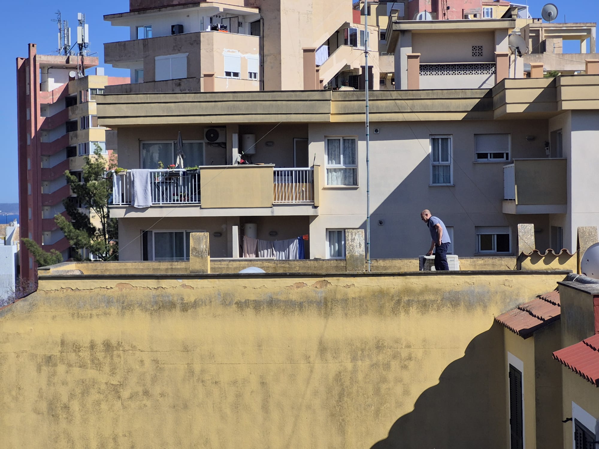 Ángel Domínguez trabajando en un tejado de Mallorca, junto a una unidad de aire acondicionado, bajo el sol